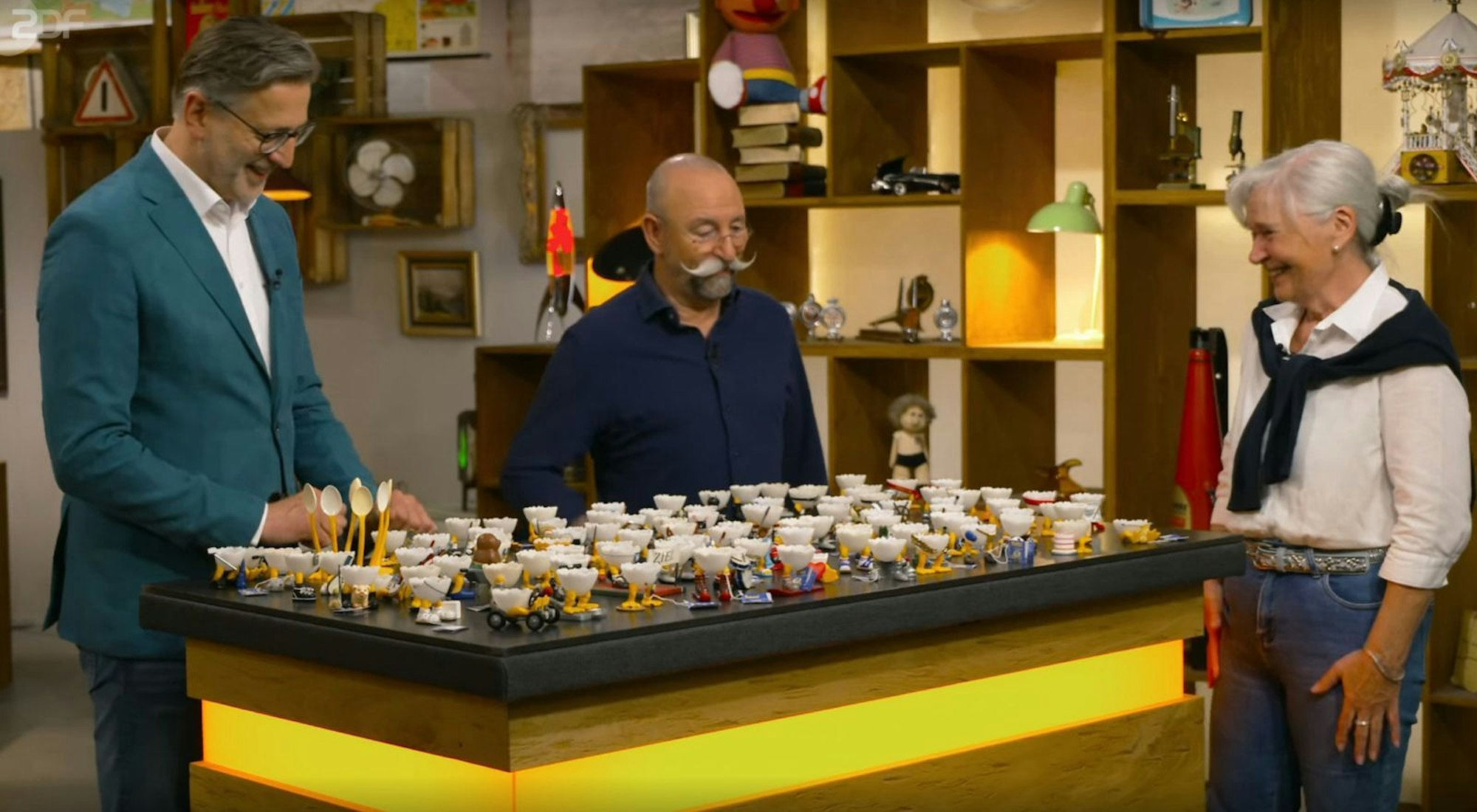 „Eieiei!“ „Horst Lichter (Mitte) war von der Kollektion sofort beeindruckt, die Kandidatin Gisela Detlev Kümmel zur Expertise überlassen hatte. (Bild: ZDF)