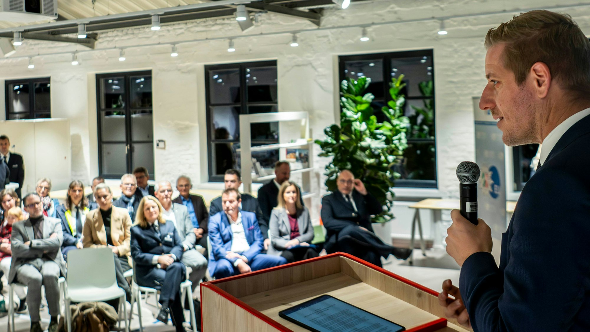 Das Bild zeigt den Landrat an einem Rednerpult. Im Hintergrund ist das Publikum zu sehen.