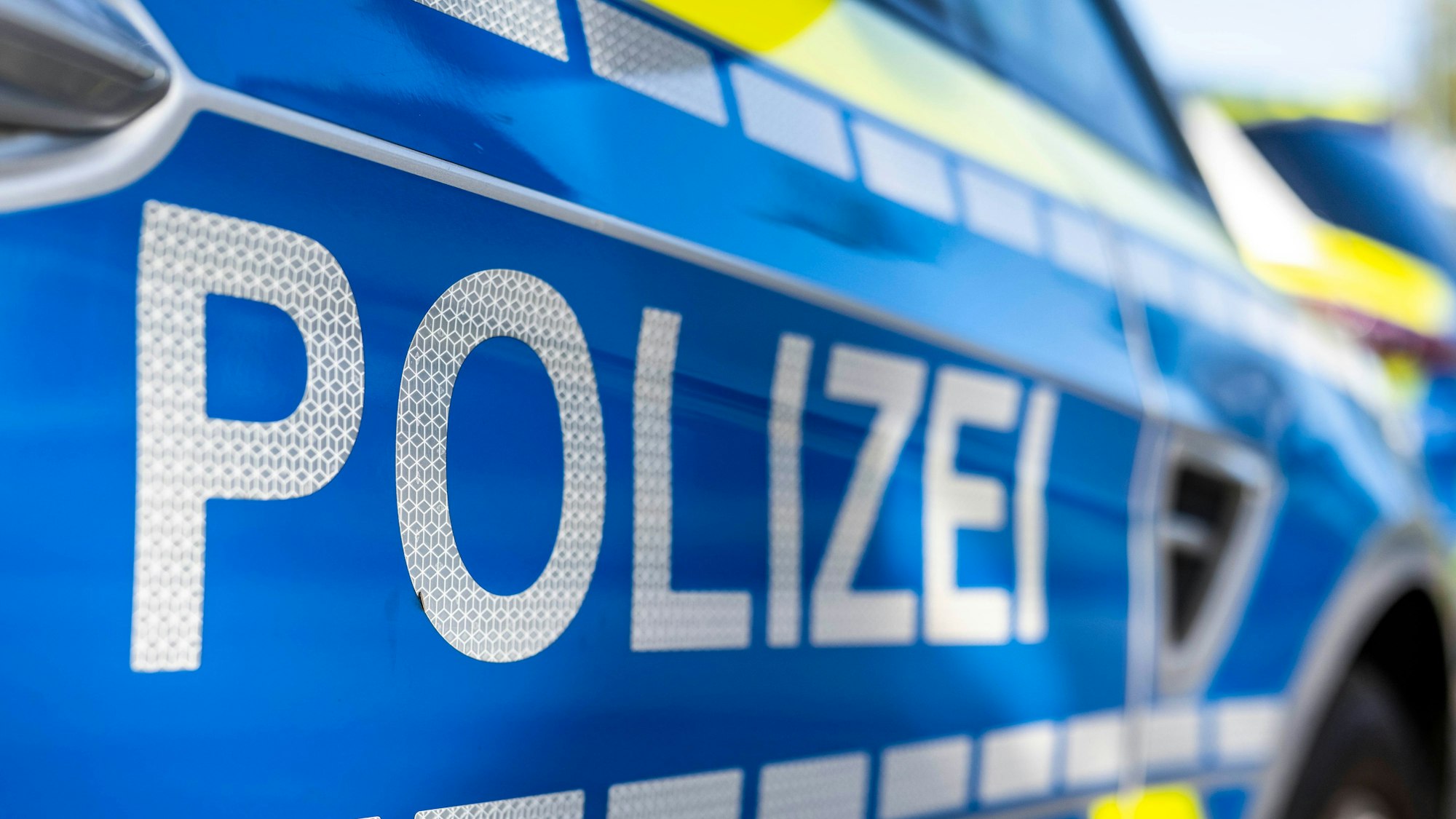 An der Tür von einem Streifenwagen steht der Schriftzug „Polizei“.