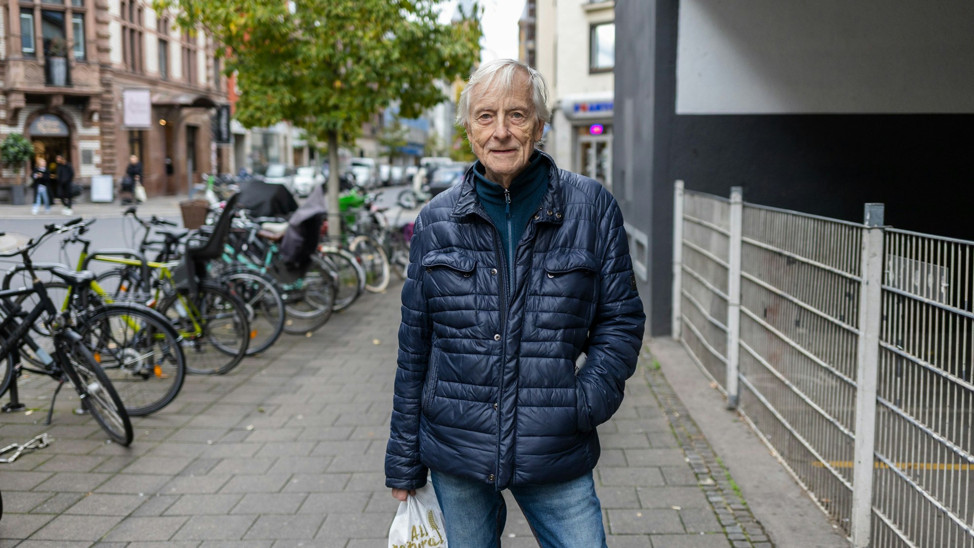 Ein älterer Mann mit Brötchentüten in der Hand steht auf der Maastrichter Straße.