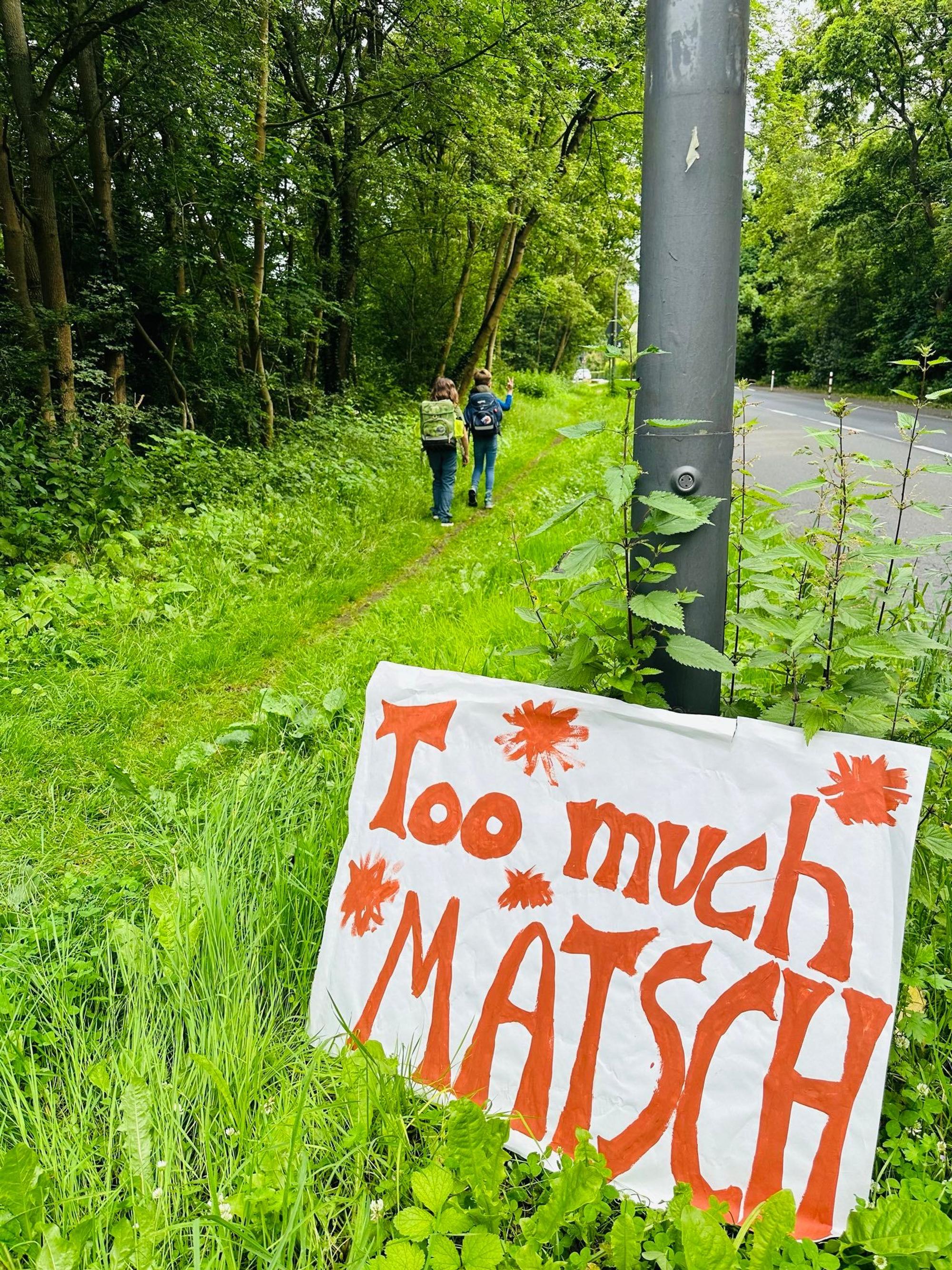 Auf einem Schild, das an einem Laternenpfahl lehnt, steht Too much Matsch.