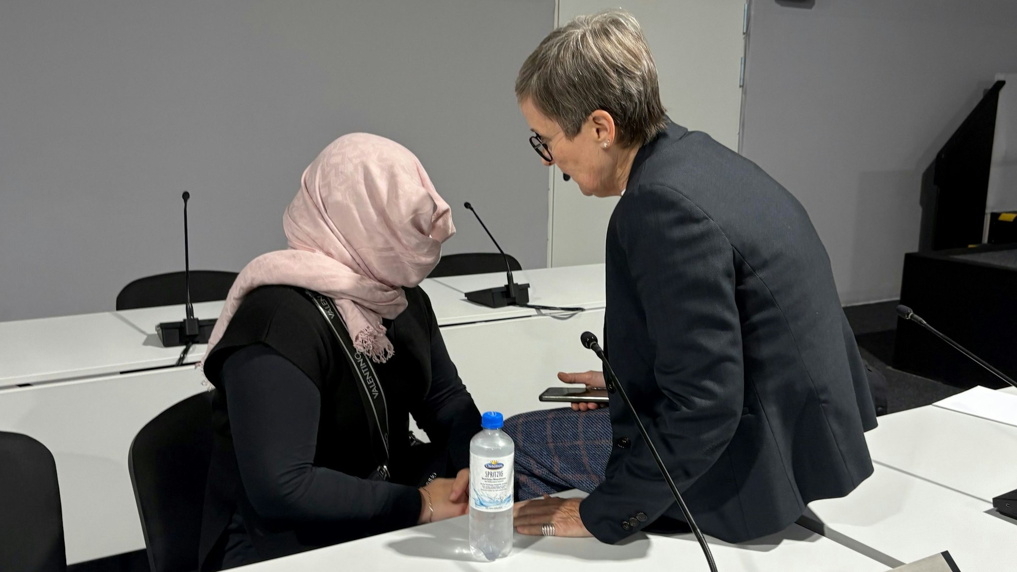 Die Angeklagte verdeckt im Amtsgericht Köln ihr Gesicht vor den anwesenden Pressefotografen. Rechts Verteidigerin Susanne Cziongalla.
