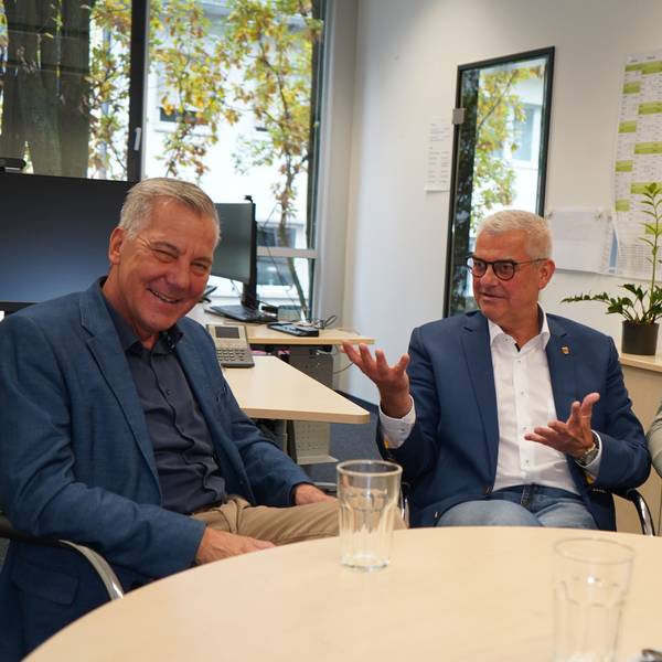 Das Foto zeigt drei Männer, die sich unterhalten.