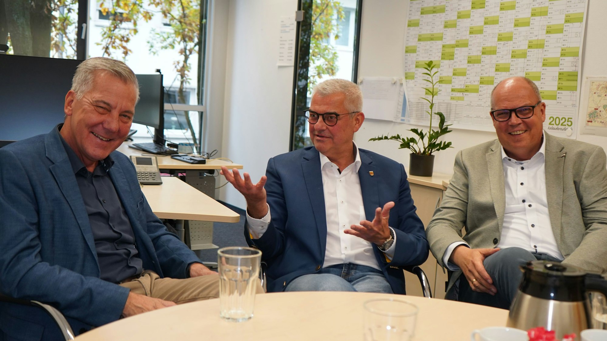 Das Foto zeigt drei Männer, die sich unterhalten.