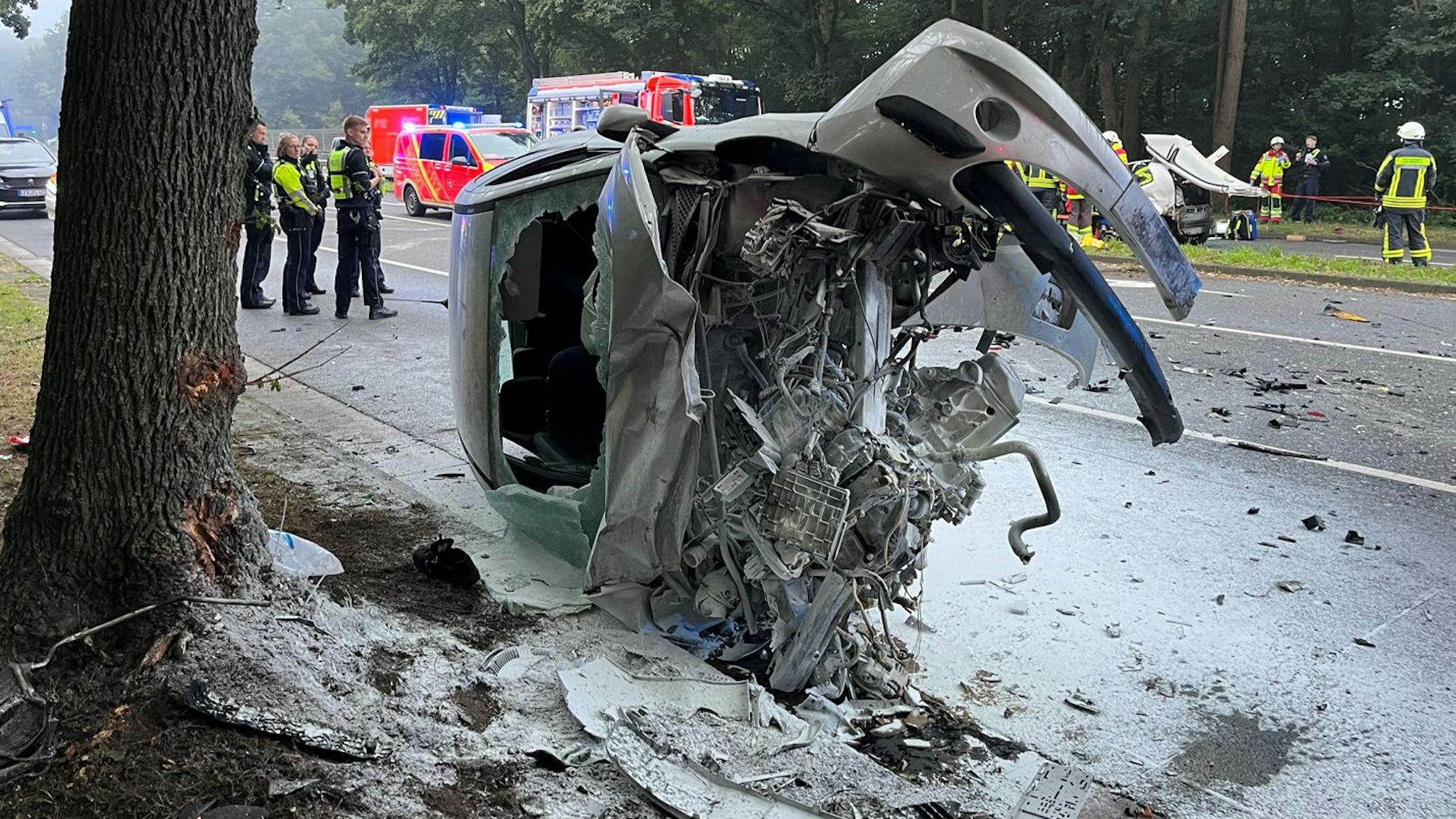 Ein Autowrack liegt ausgebrannt auf einer Straße.