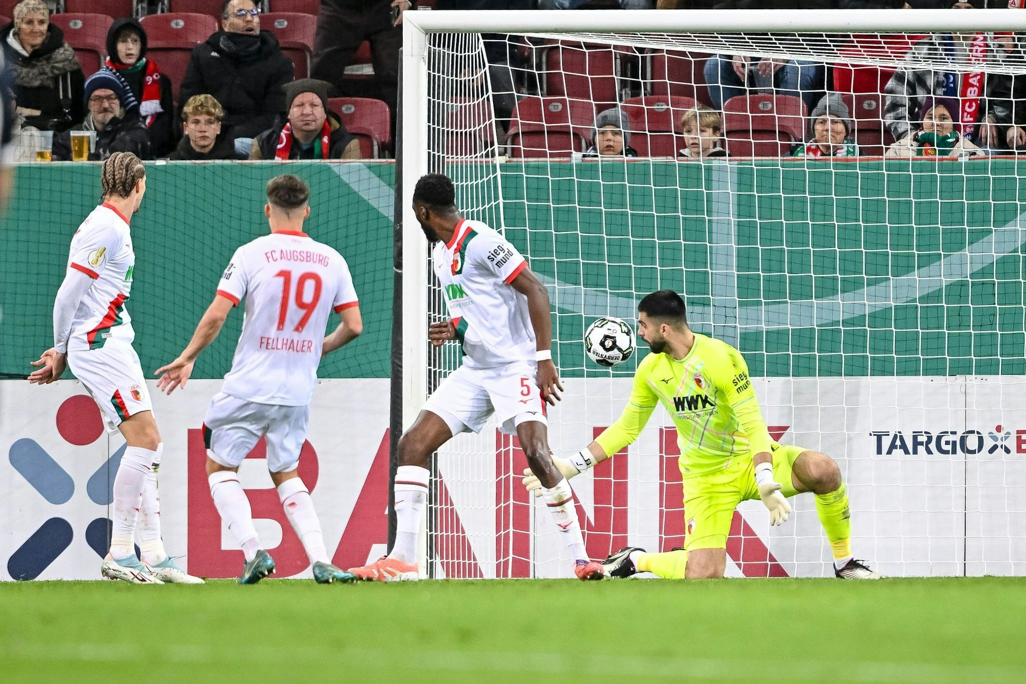 Der Schuss, der zum Augsburger Pokal-K.o. führt. Verteidiger Chrislain Matsima (M) fälscht den Ball auch noch unglücklich und damit unhaltbar ab.
