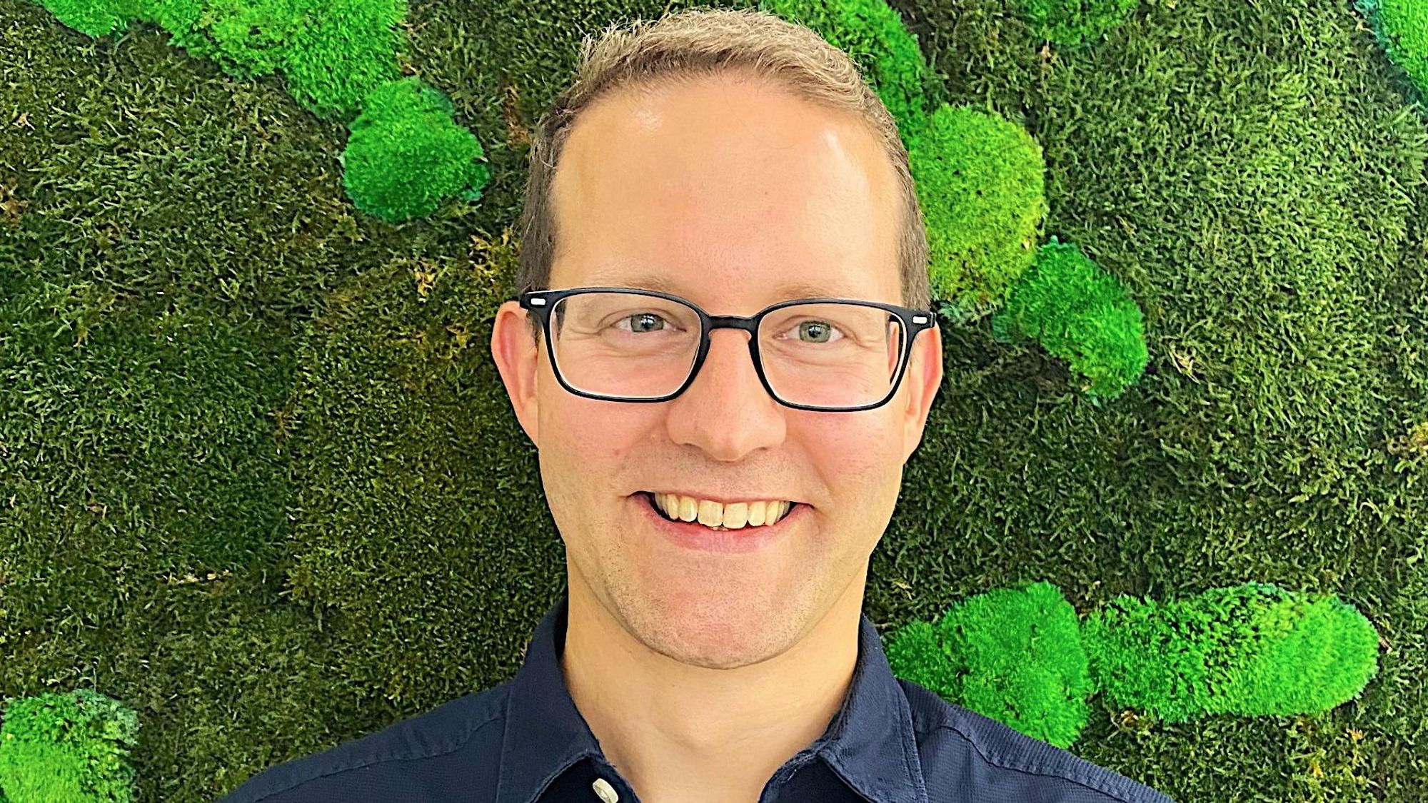 Das Porträt zeigt Dr. Markus Reichenberger von der Firma Kyon Energy vor einer grünen Wand.