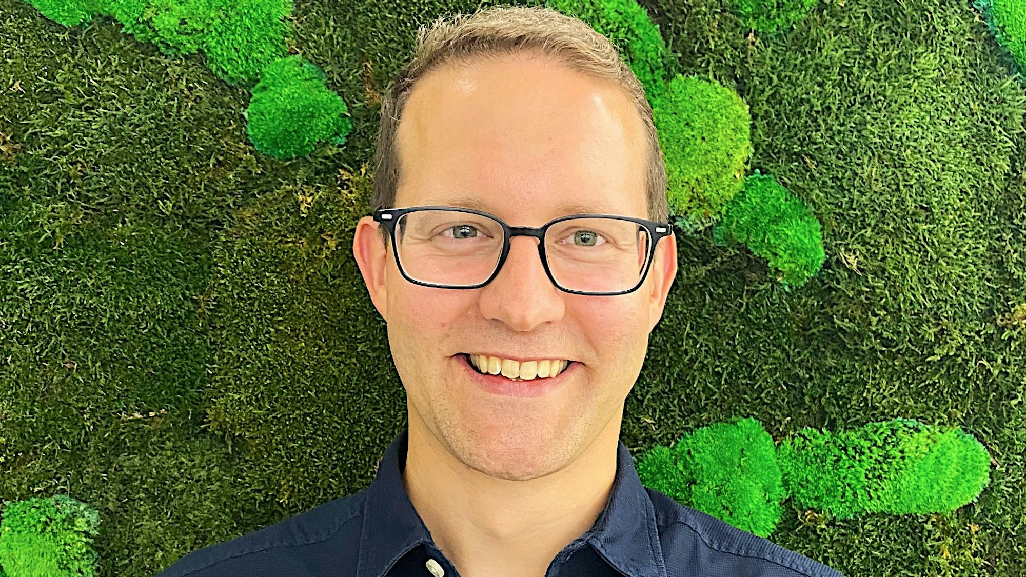 Das Porträt zeigt Dr. Markus Reichenberger von der Firma Kyon Energy vor einer grünen Wand.