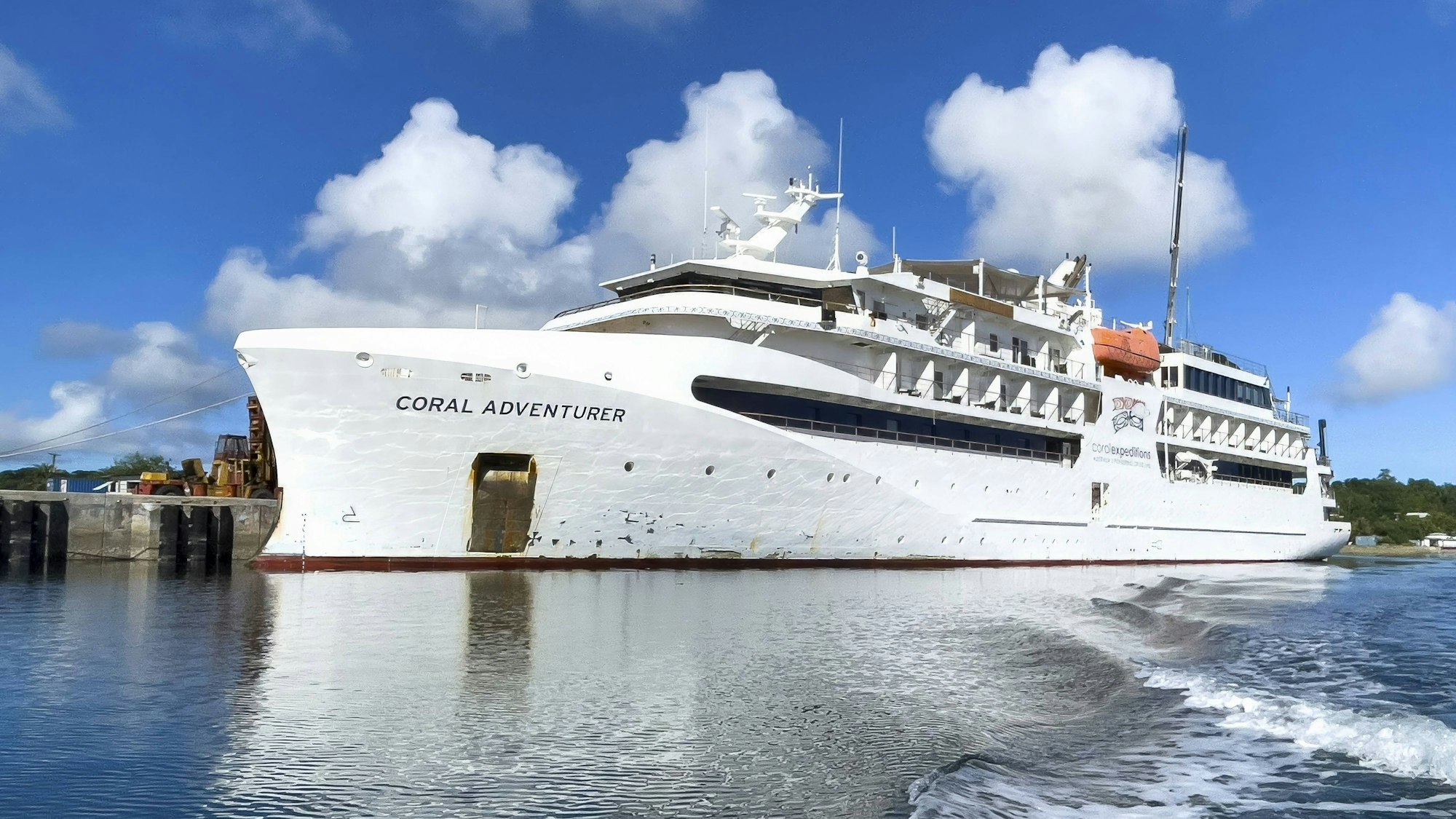 Das weiße Kreuzfahrtschiff „Coral Adventurer“ liegt am Pier.