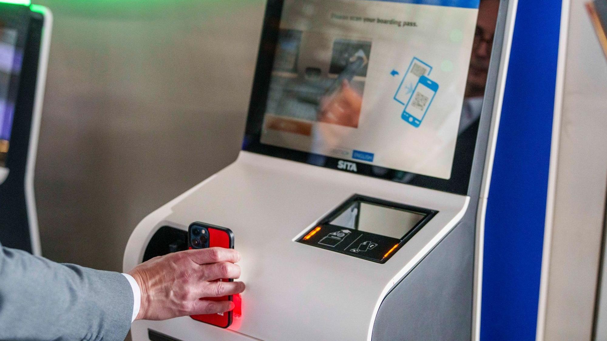 Eine Person hält ein Handy an einen Schalter. Ryanair macht Schluss mit Papier. (Archivbild)