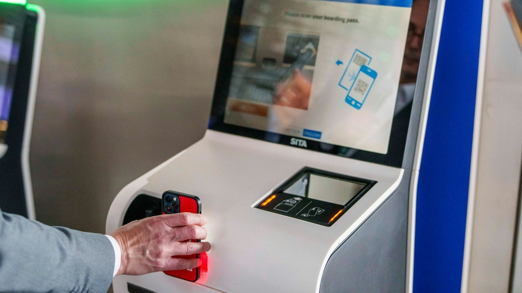 Eine Person hält ein Handy an einen Schalter. Ryanair macht Schluss mit Papier. (Archivbild)