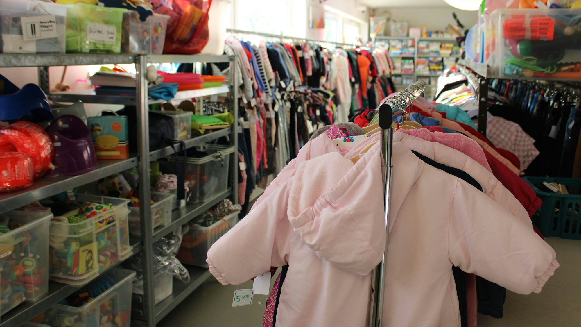 Mehrere Kinderjacken, im Hintergrund Spielsachen und Kinderkleidung.