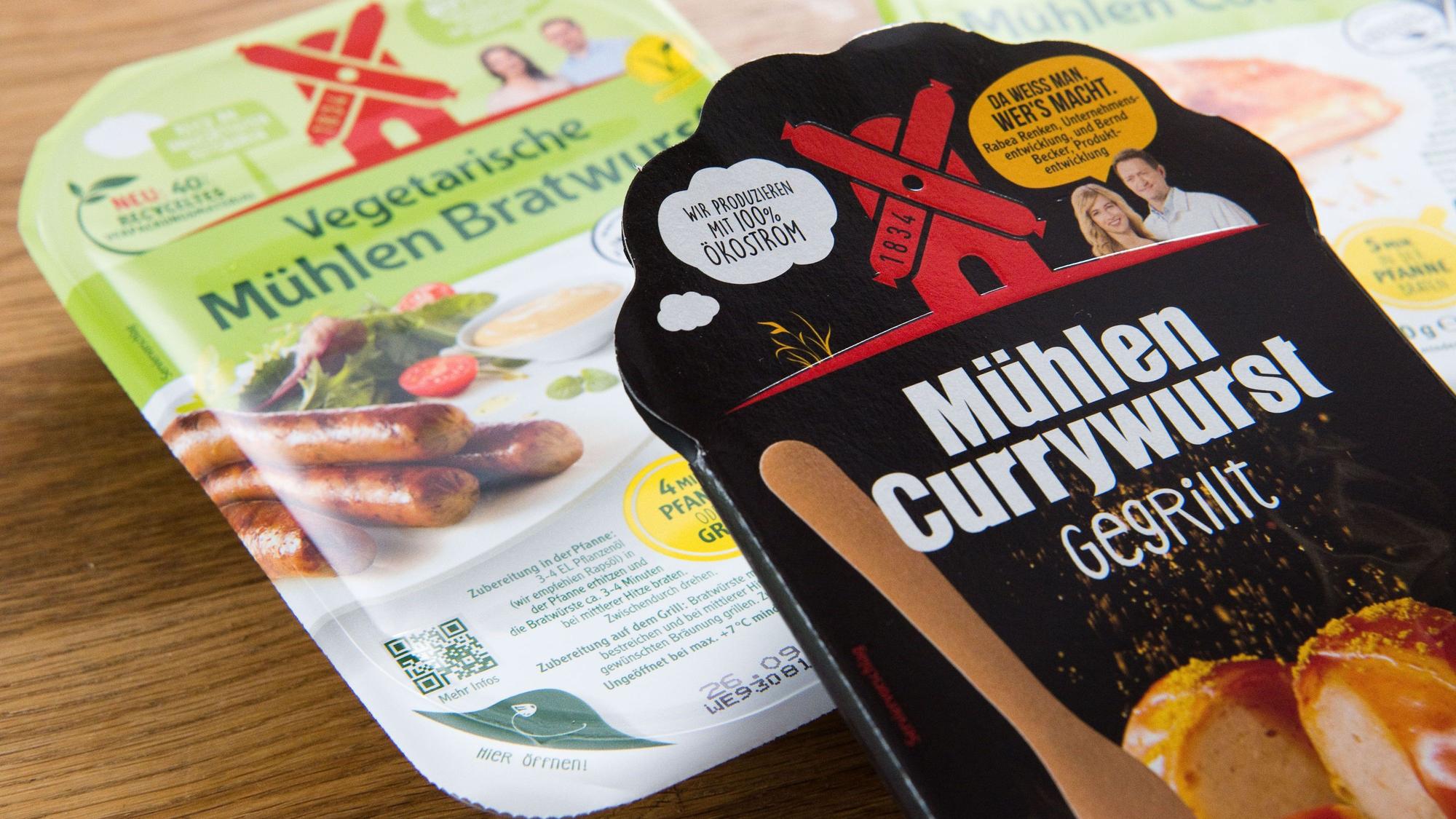 Die "Mühlen Currywurst - gegrillt" vom Hersteller Rügenwalder Mühle liegt mit vegetarischen und veganen Produkte auf einem Tisch.