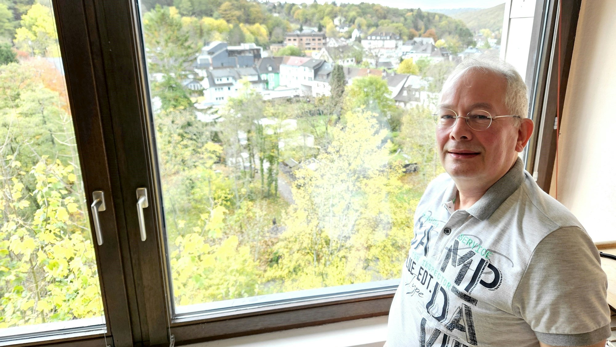 Manfred Müller steht am Fenster, im Hintergrund ist Gemünd zu sehen.