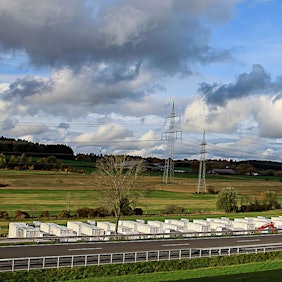 Auf 300 Metern wird an der B51 ein großes Batteriespeicherwerk gebaut. Ein roter Kran setzt die Elemente auf die Fundamente.