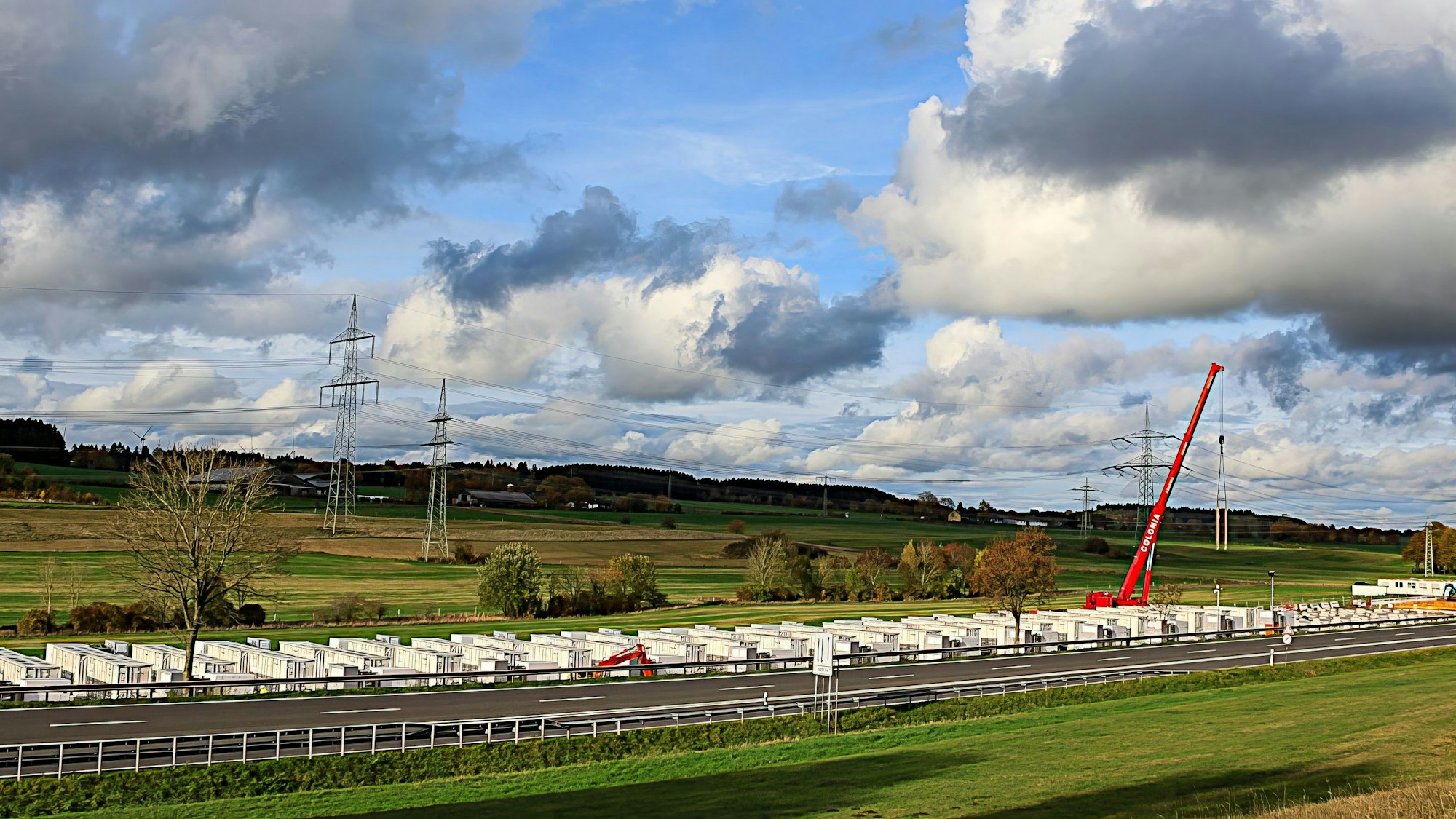 Auf 300 Metern wird an der B51 ein großes Batteriespeicherwerk gebaut. Ein roter Kran setzt die Elemente auf die Fundamente.