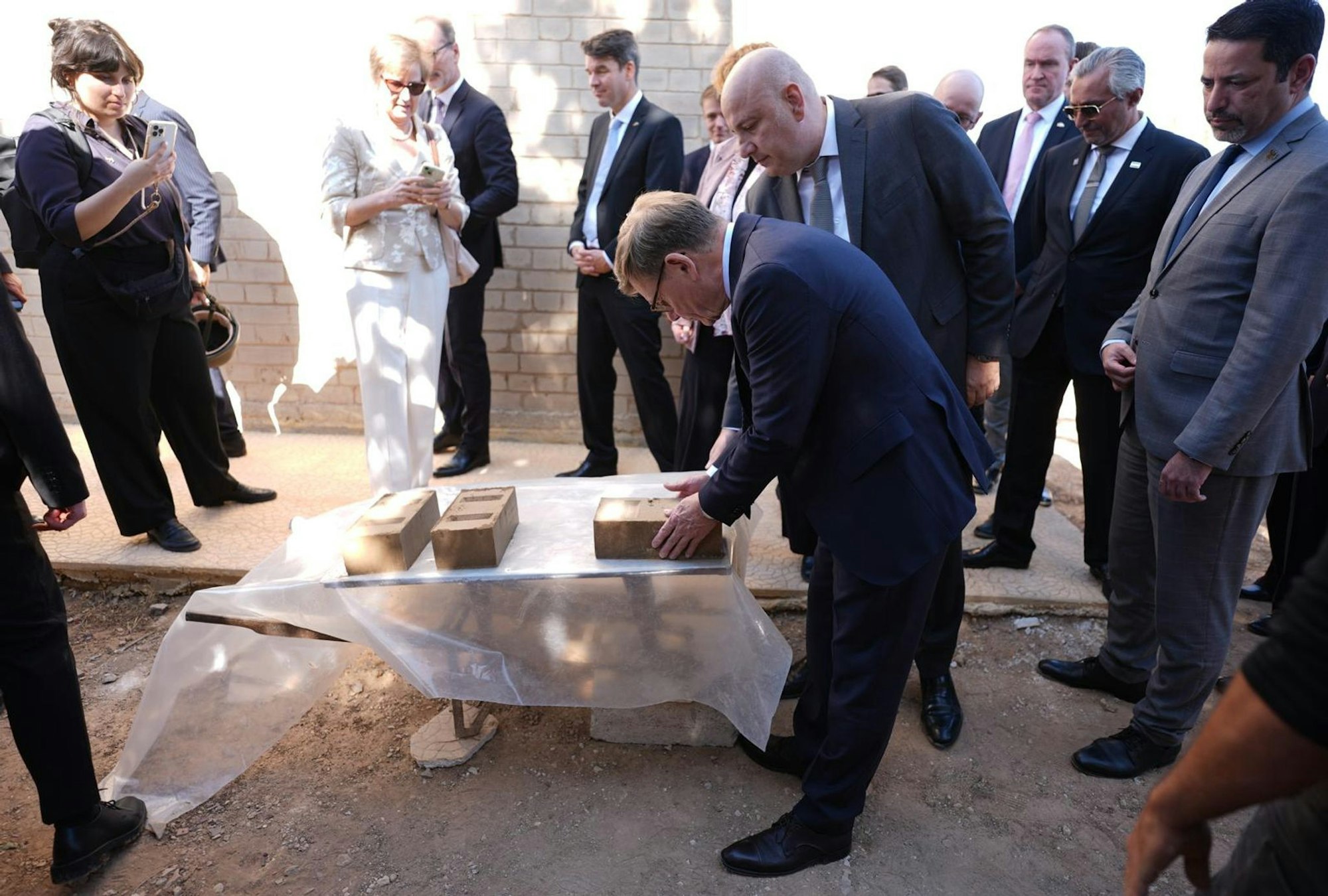 Außenminister Johann Wadephul (CDU) macht sich ein Bild von einem Projekt, das Binnenvertriebenen ermöglichen soll, günstig mit Lehmziegeln zu bauen.