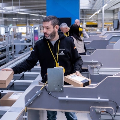 Mehrere Mitarbeiter sortieren kleine Pakete in den Multiformatsorter ein.