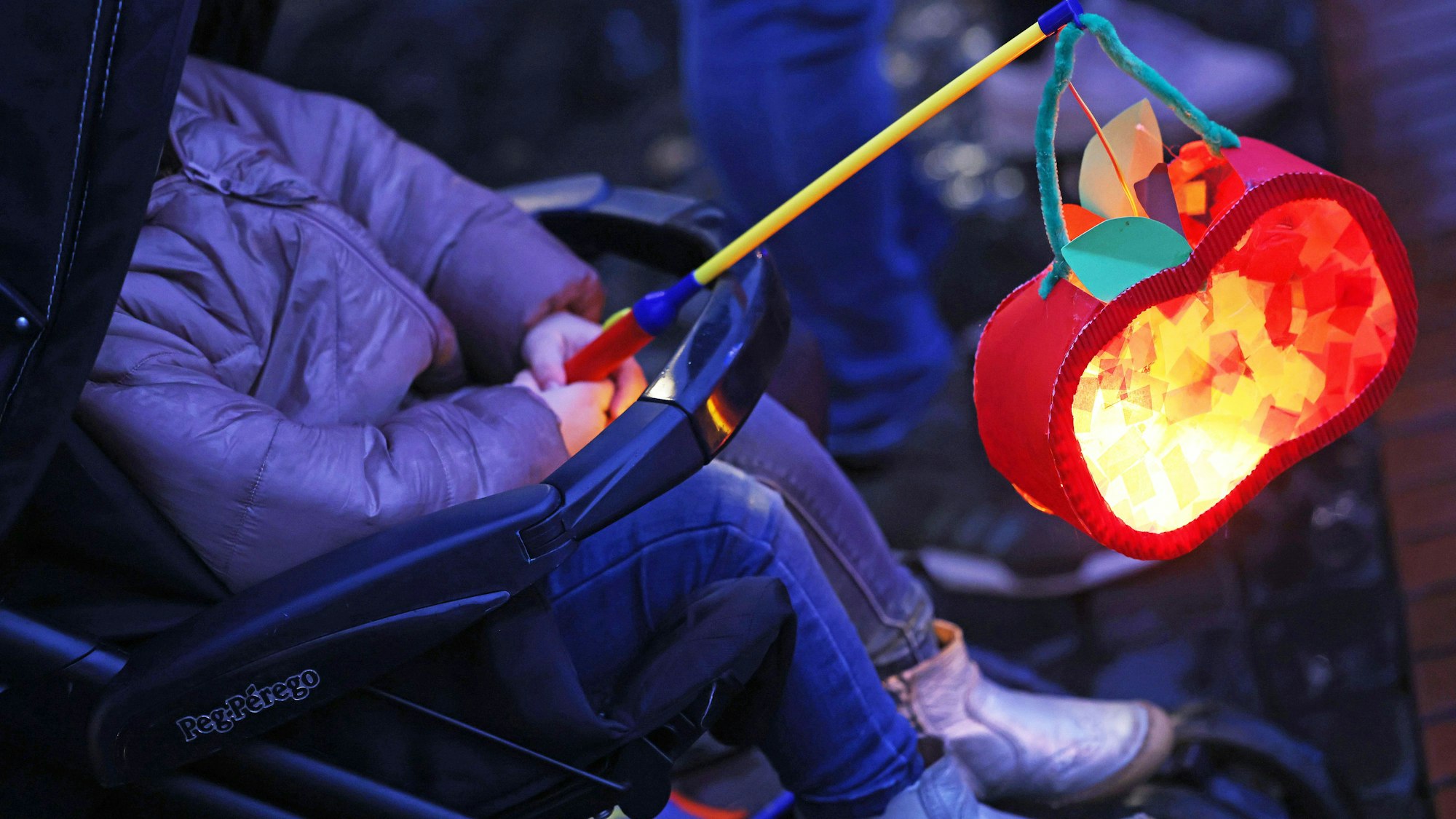 Eltern und Kinder gehen mit Laternen beim Martinsumzug durch die Innenstadt.
