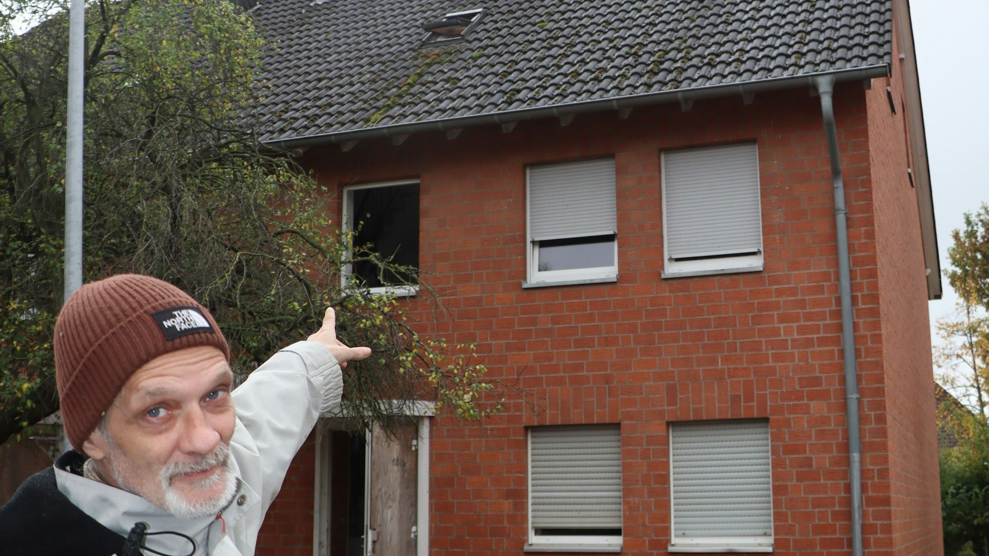 Zu sehen ist, wie ein Mann auf ein Haus deutet.