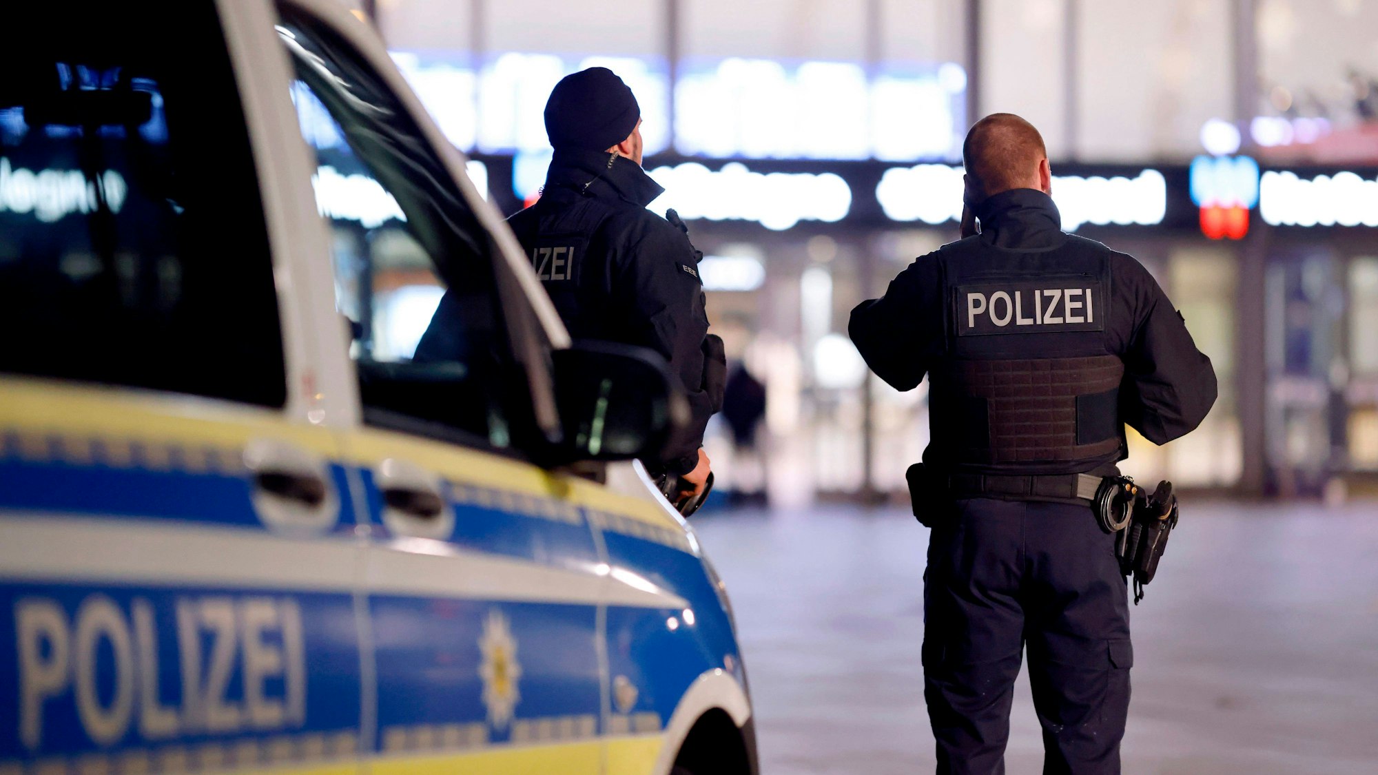 Beamte der Polizei stehen mit einem Fahrzeug der Polizei auf dem Bahnhofsvorplatz in Köln.