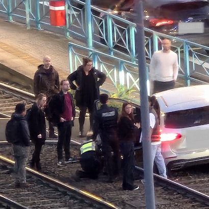 Ein Auto steht im Gleisbett der KVB, mehrere Menschen stehen darum