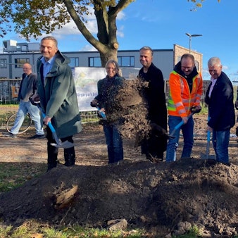 Zu sehen sind Männer und Frauen, die Spaten in den Händen halten und Erde schaufeln.