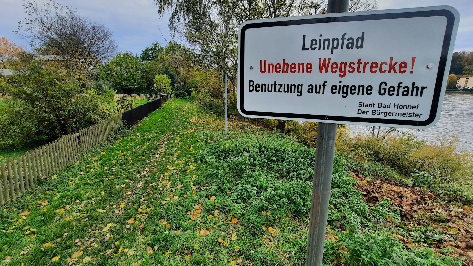 Der Leinpfad in Bad Honnef, im Vordergrund ein Schild mit der Warnung „Unebene Wegstrecke“.