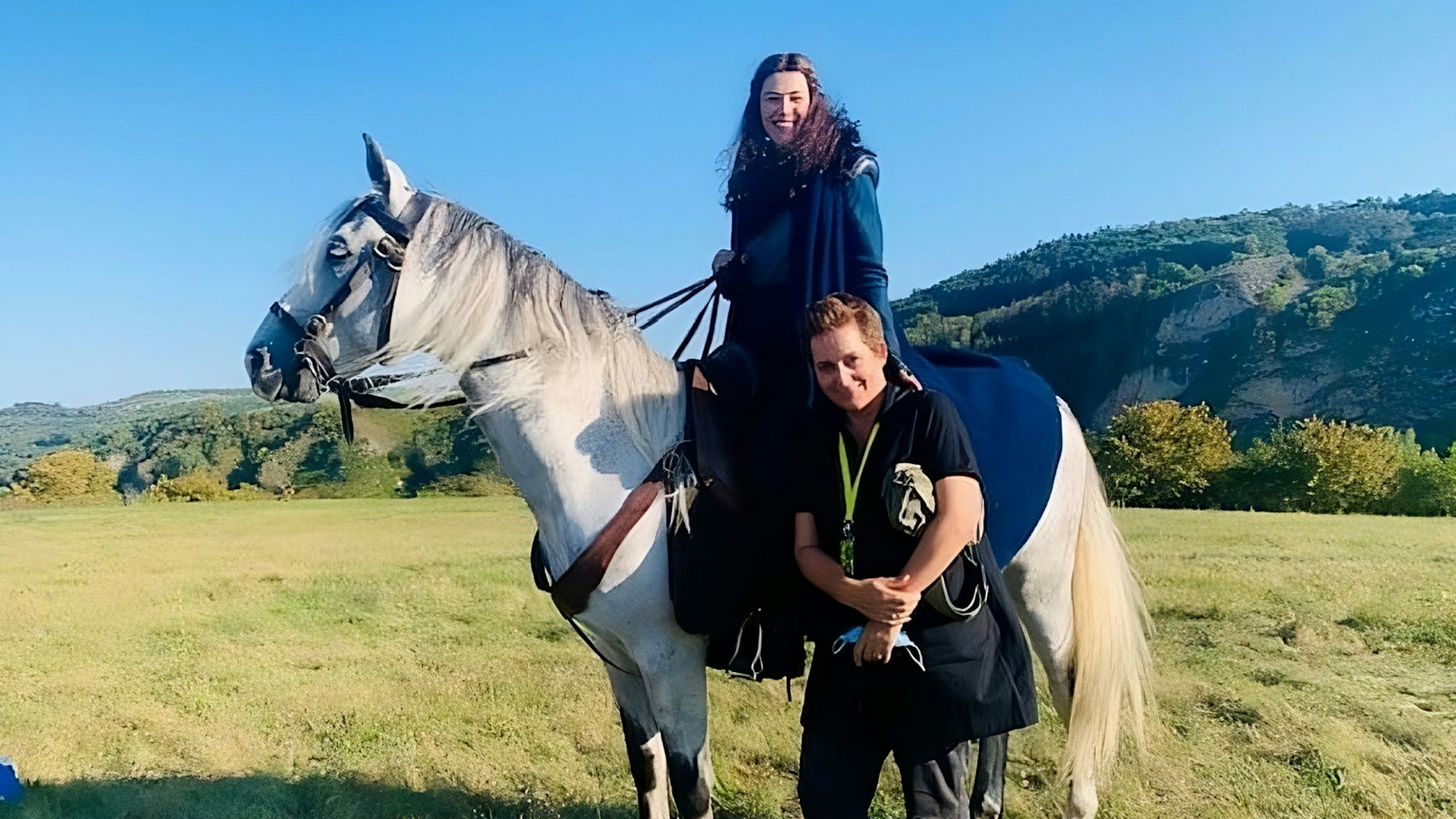 Schauspielerin Rosamund Pike sitzt auf einem Pferd und legt ihre Hand auf Regisseurin Uta Briesewitz.