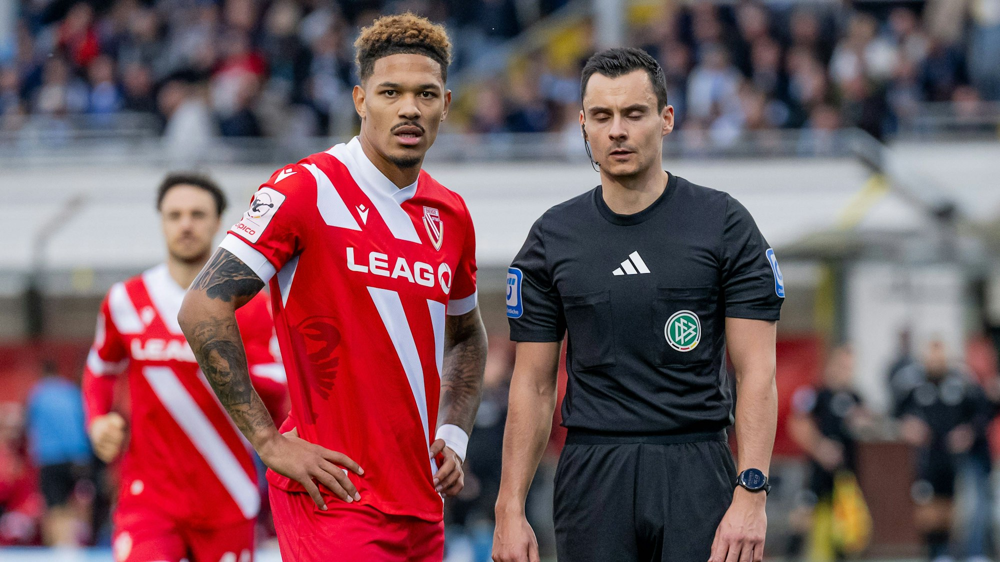 Justin Butler von Energie Cottbus und Schiedsrichter Konrad Oldhafer beim Drittligaspiel in München.