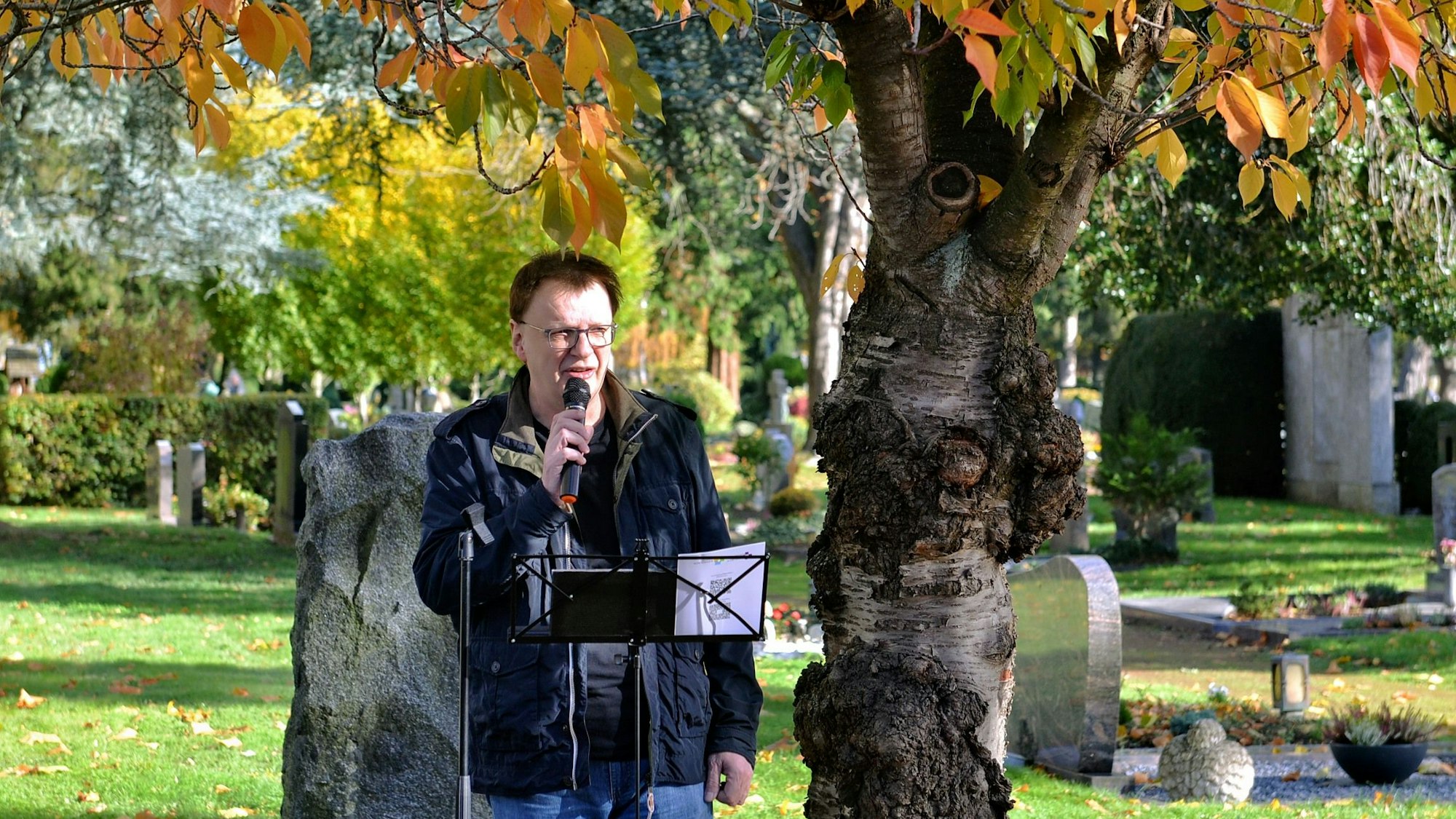 Jens Schramm spricht auf dem Friedhof in ein Mikrofon.