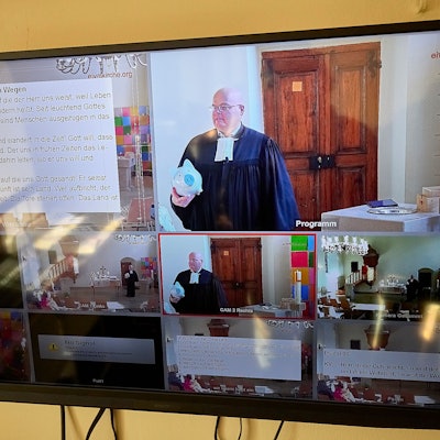 Auf einem Computermonitor sind verschiedene Bilder aus der Übertragung eines Gottesdienstes in Hellenthal zu sehen.