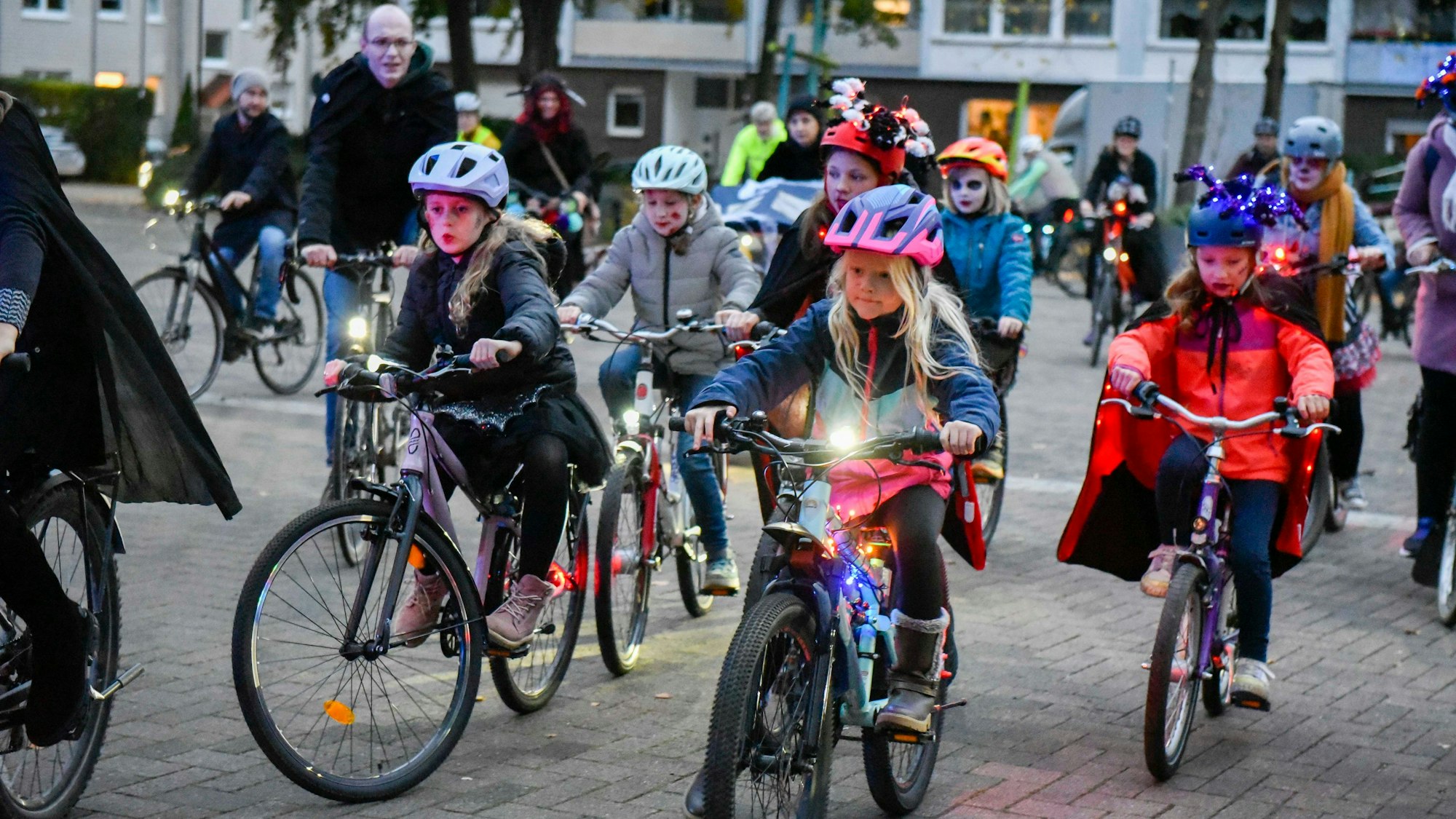 Zu sehen sind Kinder in Halloween-Kostümen auf Fahrrädern.