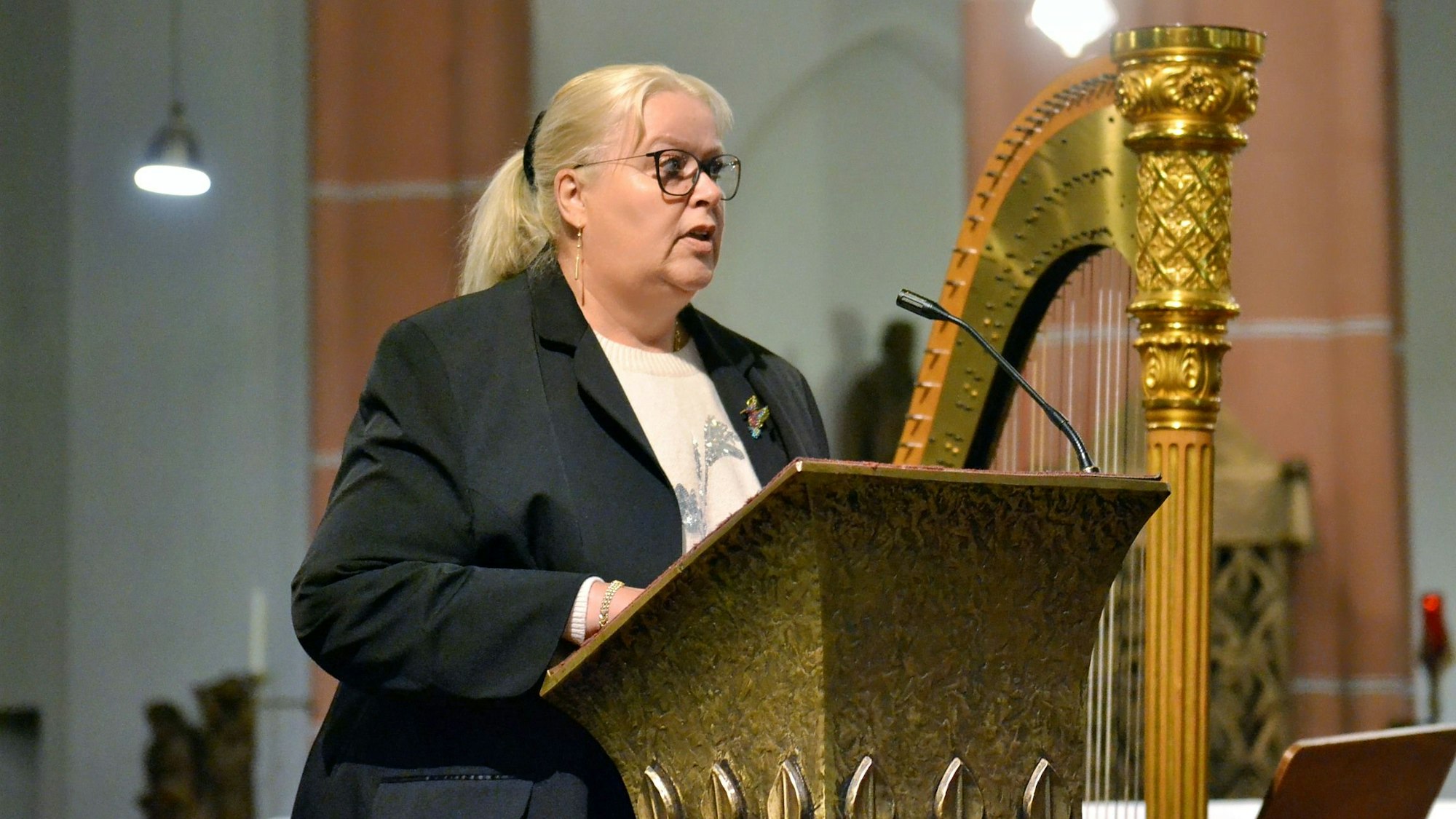 Annette Schuster, Initiatorin des Benefizkonzerts, steht am Rednerpult der Herz-Jesu-Kirche.