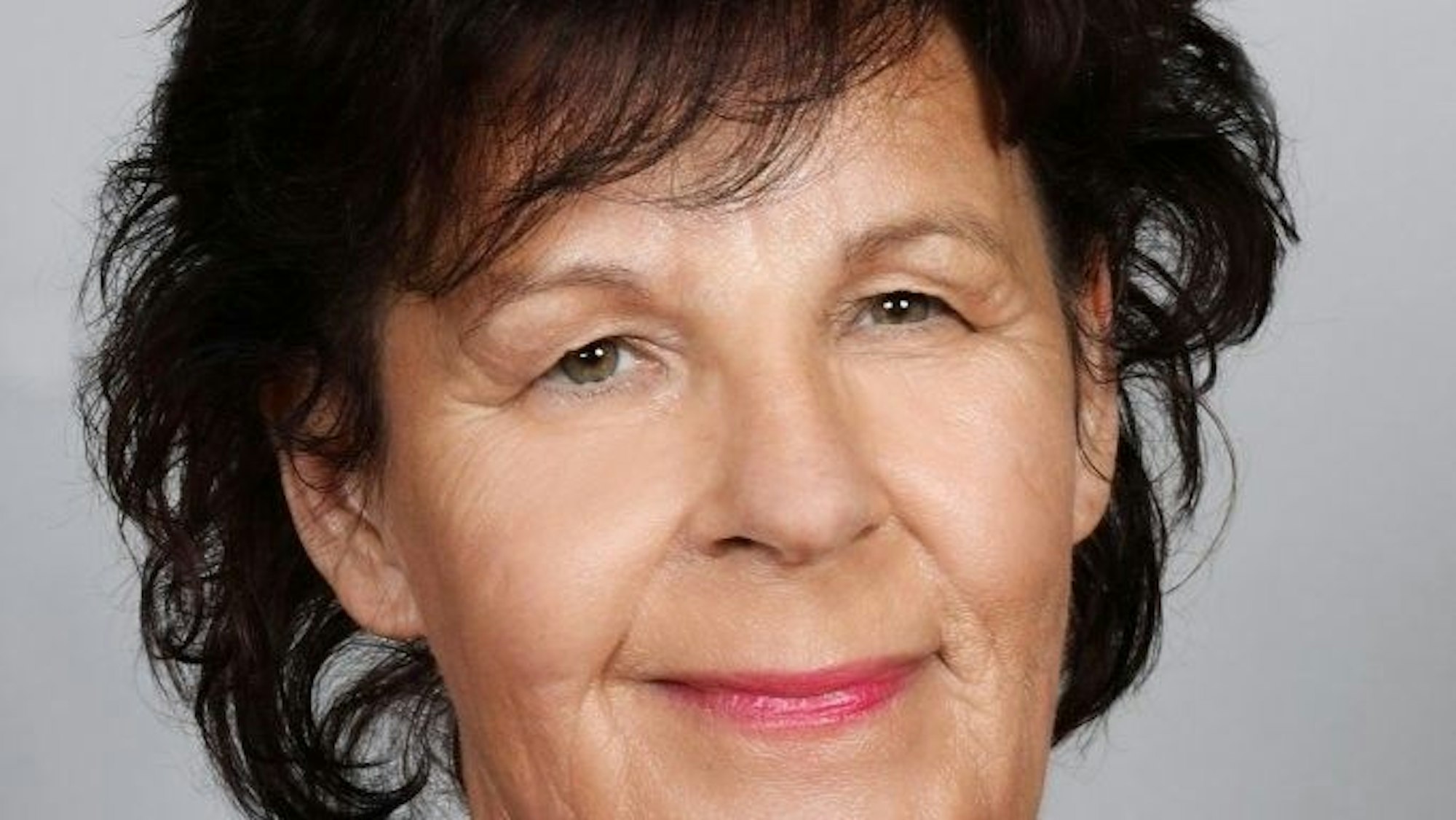 Eine Frau mit schwarzem Haar und rotem Halstuch blickt lächelnd in die Kamera.