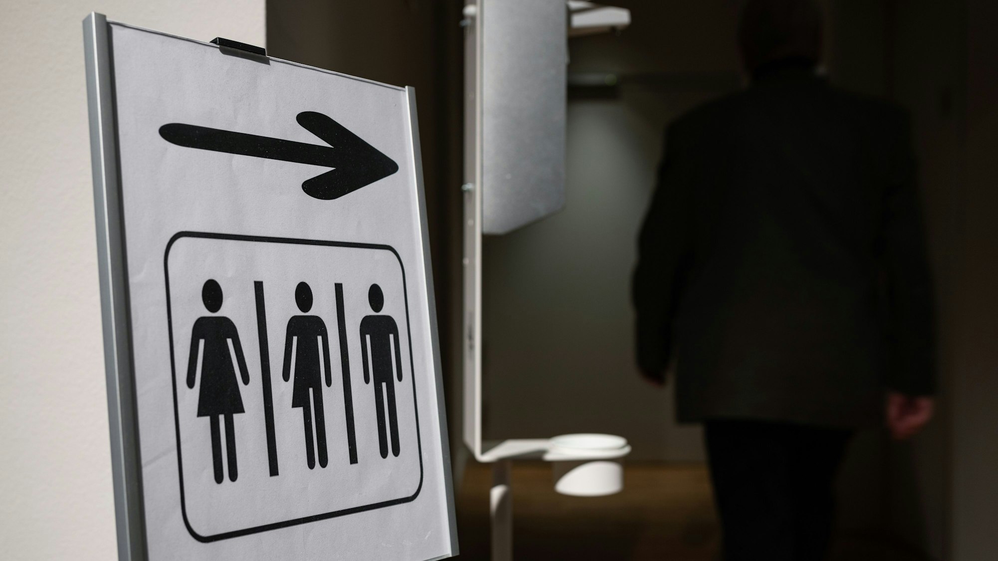 Ein Aufsteller weist die Richtung zu Unisex-Toiletten.