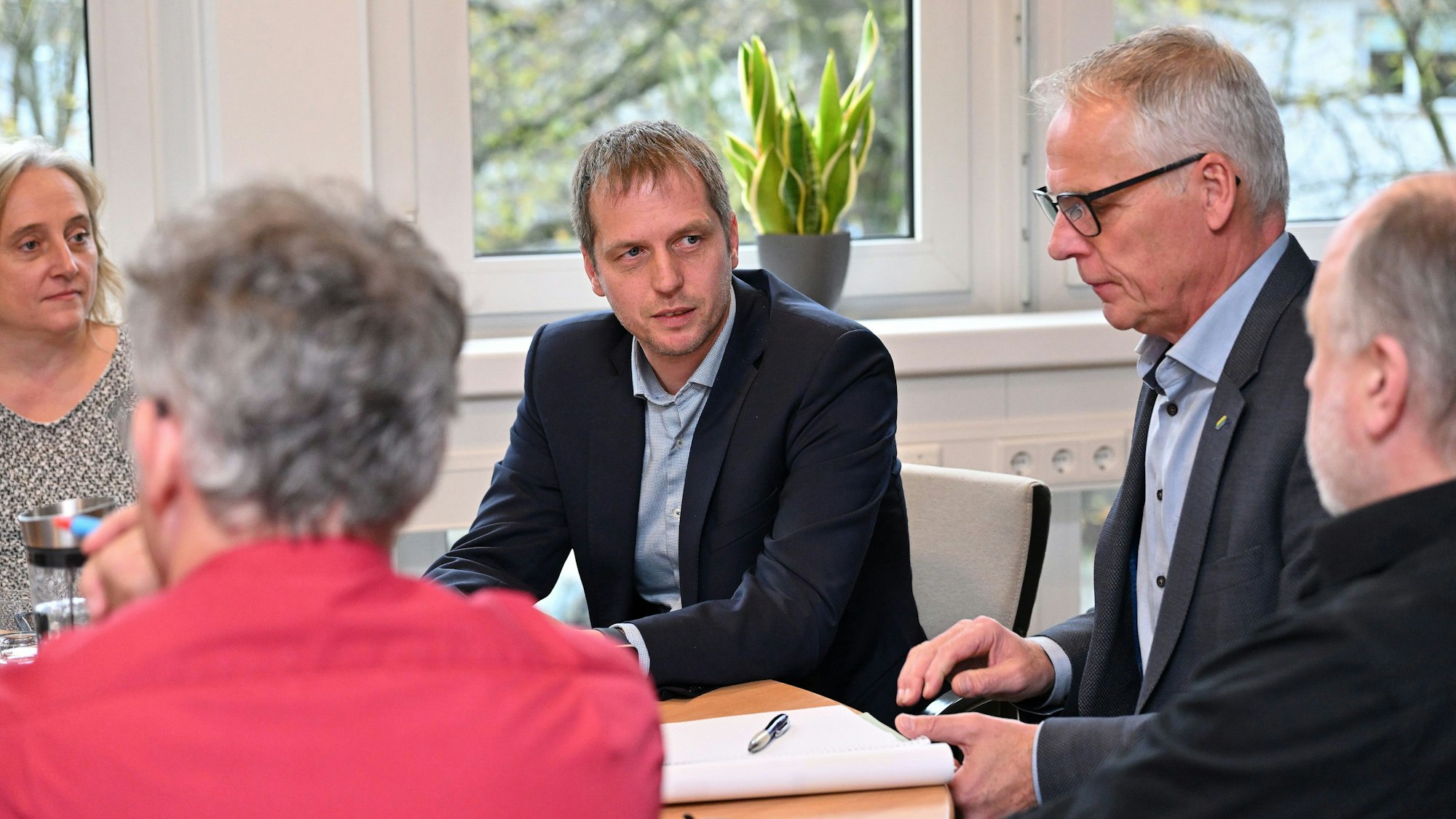 Mehrere Menschen sitzen um einen runden Tisch.