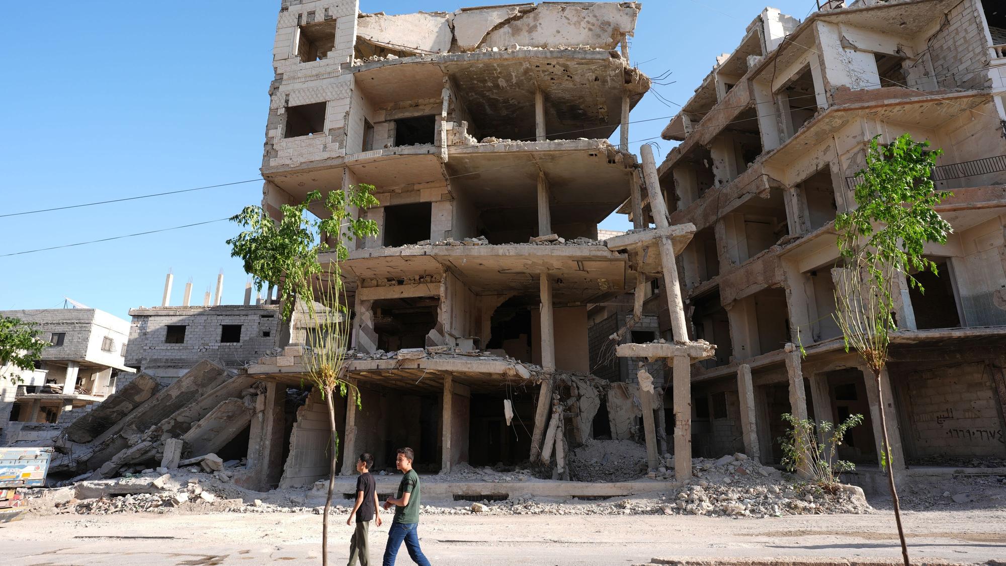 Syrien, Harasta: Bewohner gehen an einer Ruine vorbei.