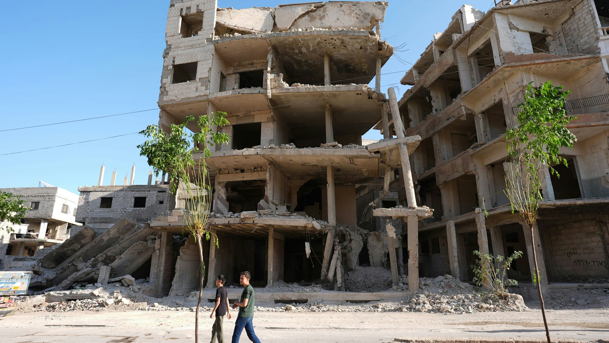 Syrien, Harasta: Bewohner gehen an einer Ruine vorbei.