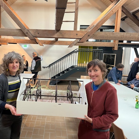 Zwei Frauen halten das Modell eines ausgebauten Dachbodens.