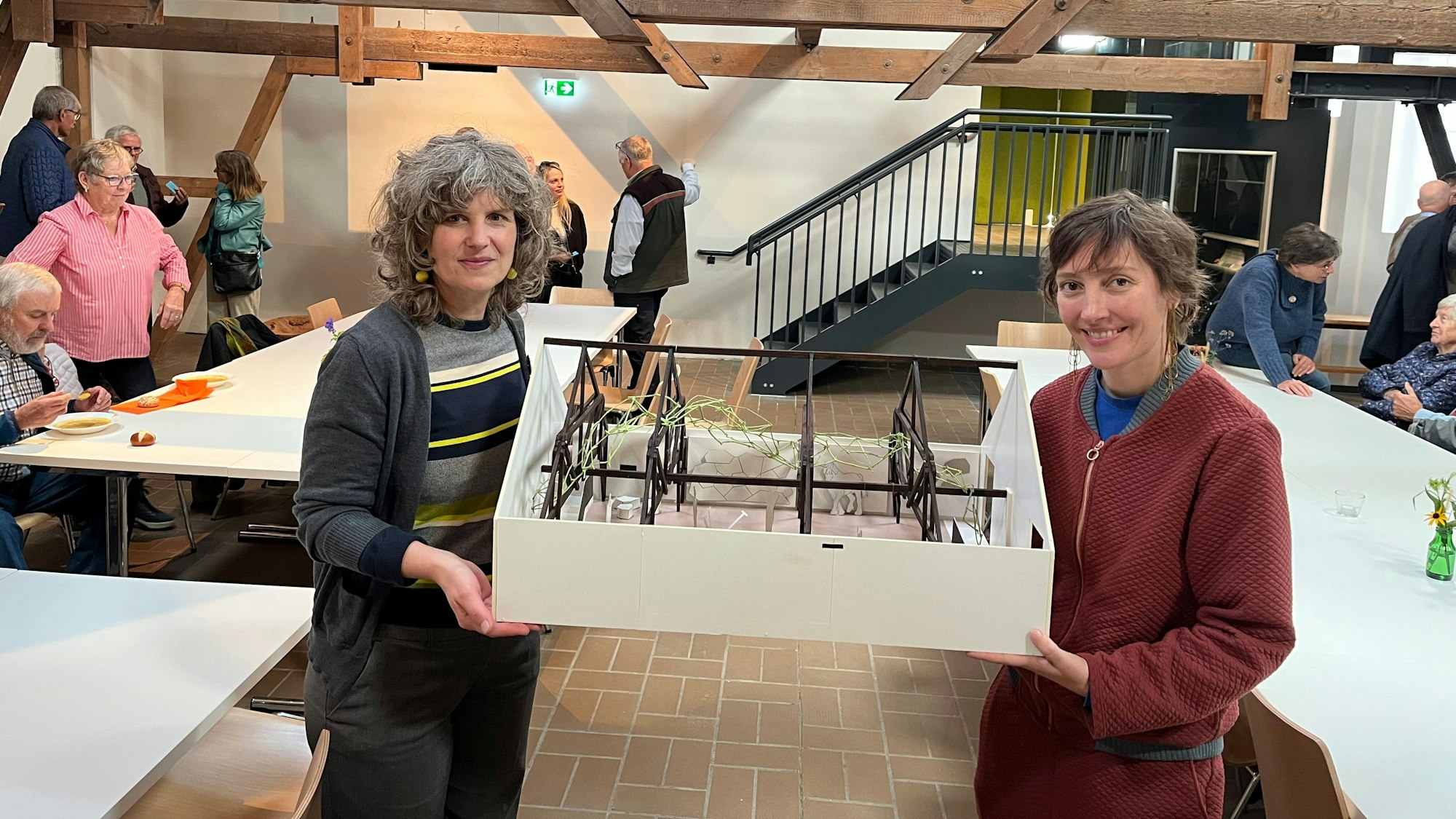 Zwei Frauen halten das Modell eines ausgebauten Dachbodens.