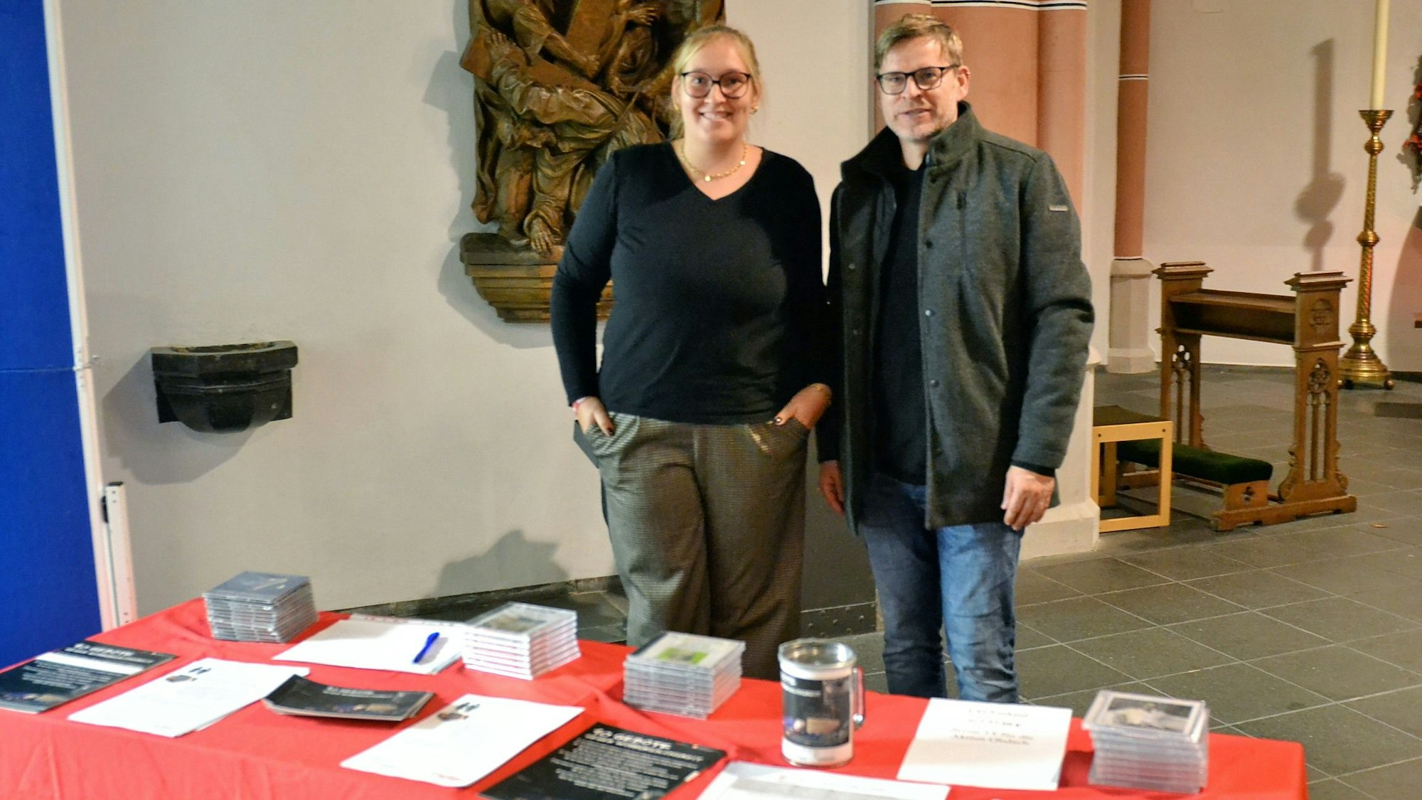 Hinter einem Tisch mit Broschüren, Infozetteln und einer Spendendose stehen Rebecca Kempf und Markus Niederstein von der Caritas-Wohnungslosenhilfe.