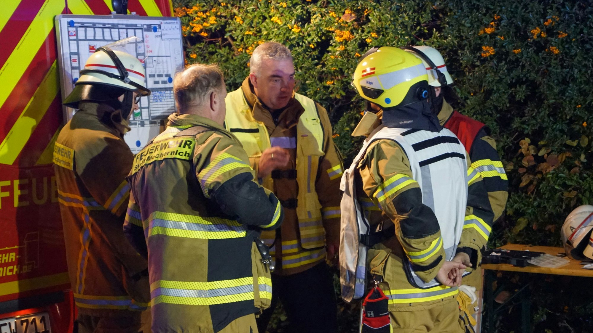 Jens Schreiber, Leiter der Feuerwehr der Stadt Mechernich, steht mit vier weiteren Feuerwehrleuten zusammen und bespricht sich mit ihnen.