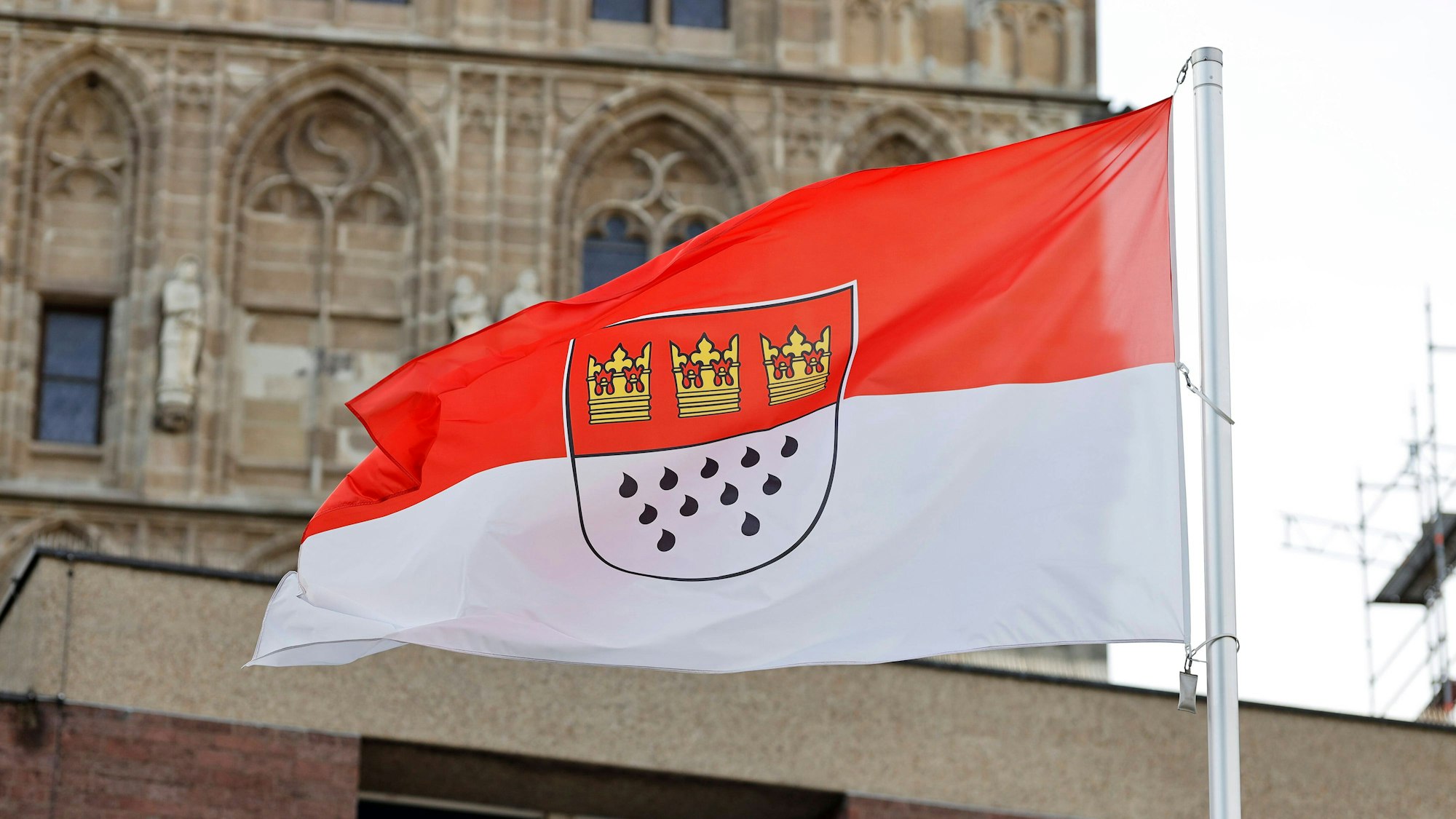 Eine Flagge am Rathaus zeigt die Kölner Farben Rot und Weiß sowie das Stadtwappen mit den drei Kronen und elf Tränen.