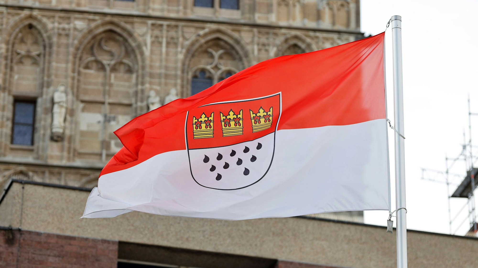 Eine Flagge am Rathaus zeigt die Kölner Farben Rot und Weiß sowie das Stadtwappen mit den drei Kronen und elf Tränen.