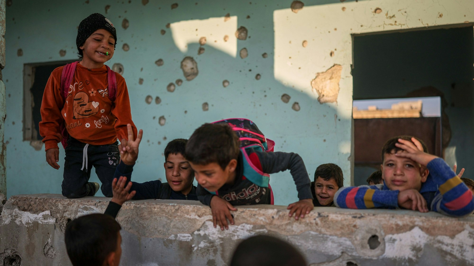 dpatopbilder - PRODUKTION - 19.10.2025, Syrien, Maar Schmarin: Schüler spielen im Hof der Grundschule von Maar Schmarin im Dorf Maar Schmarin in der Region Idlib. Die Wände der Schule sind von Einschusslöchern übersät. Foto: Ghaith Alsayed/AP/dpa +++ dpa-Bildfunk +++