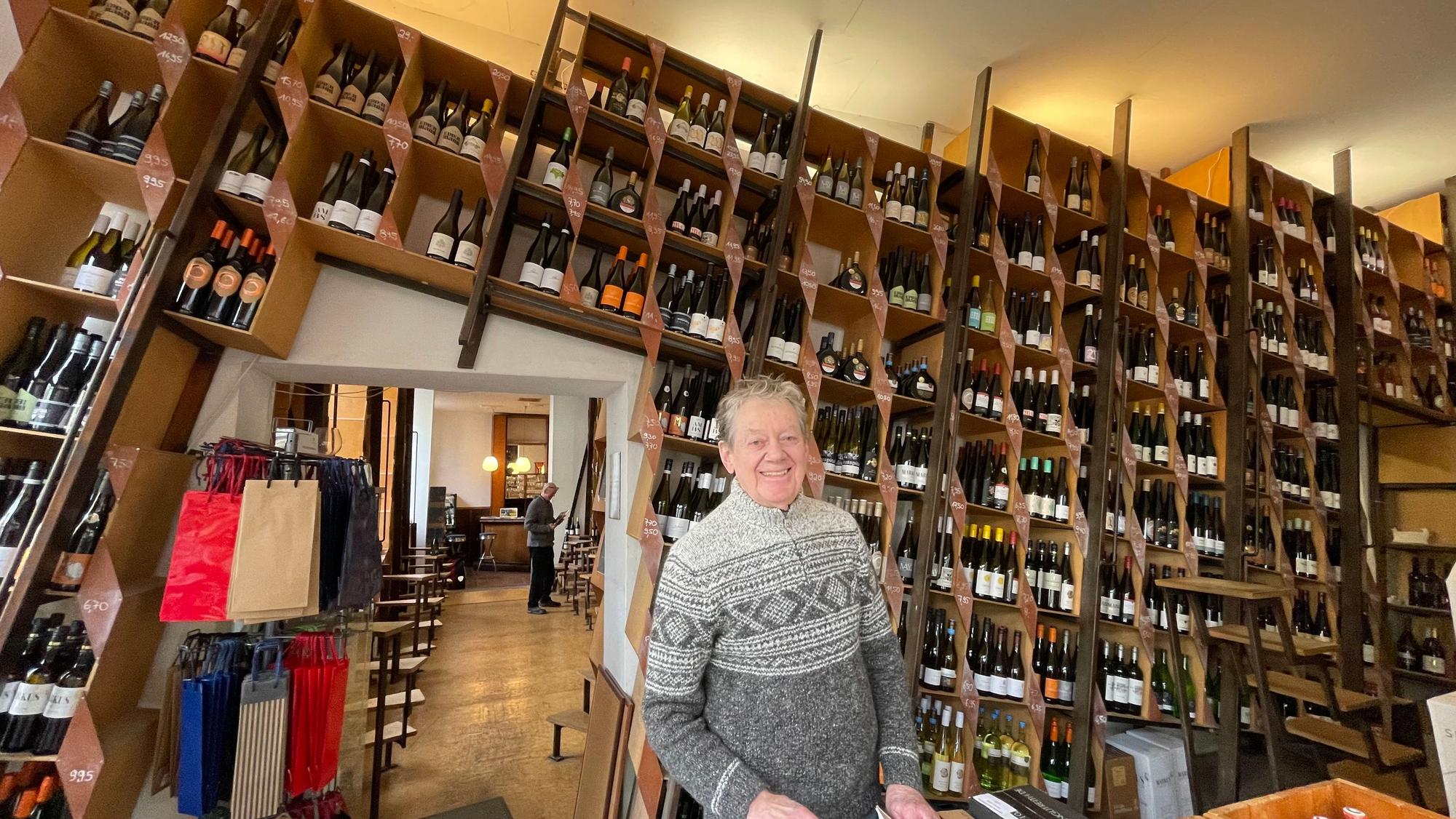 Ein Mann steht in einem großen Raum, an dessen Wand zahlreiche Weinregale nebeneinander stehen.