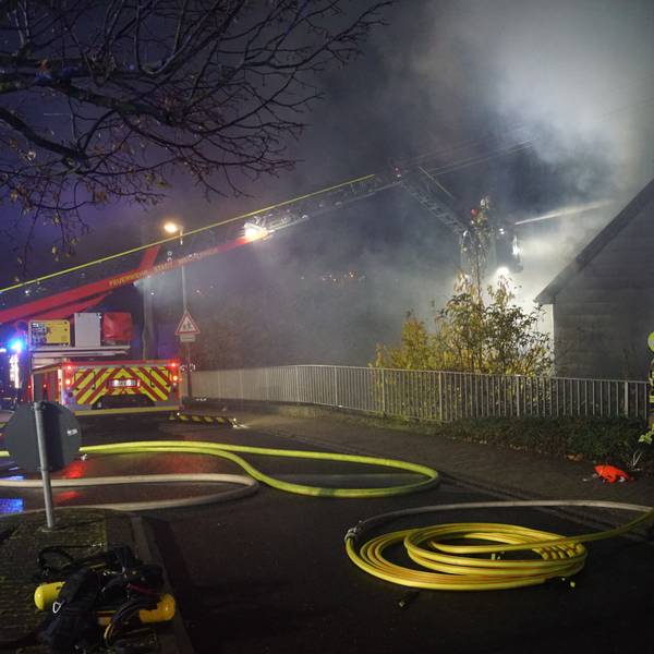 Die Drehleiter der Feuerwehr Mechernich steht auf der Straße. Aus dem Korb wird ein brennendes Haus gelöscht.