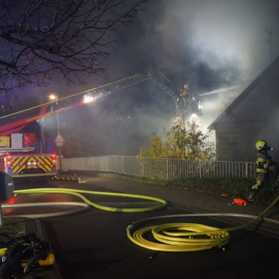 Die Drehleiter der Feuerwehr Mechernich steht auf der Straße. Aus dem Korb wird ein brennendes Haus gelöscht.