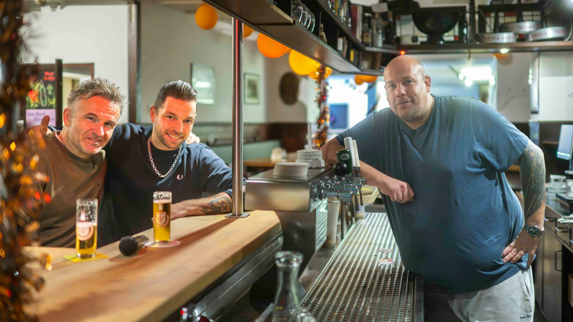 Der Wirt steht hinter der Theke, die Musiker davor.